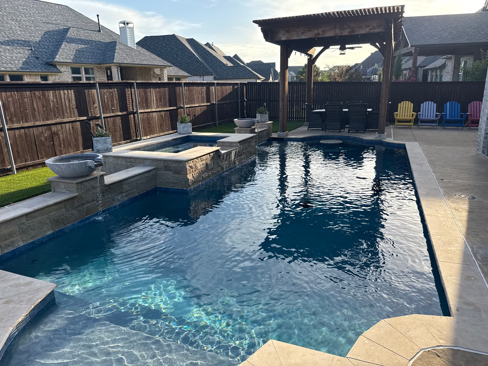 Custom pool with stone spa, scupper water bowls, and a pergola dining area